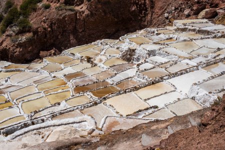 detail of the mountain salt pans with the white of the salt and the brown of the water which is turning into salt with evaporation in Peru in South America