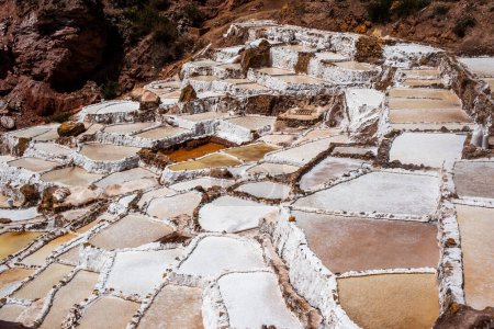 detail of the mountain salt pans with the white of the salt and the brown of the water which is turning into salt with evaporation in Peru in South America