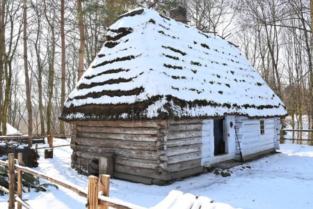 Photo for Lublin, Poland. 02/08/2023. Old Polish wooden thatched cottage covered in snow - winter landscape on a sunny day - Royalty Free Image