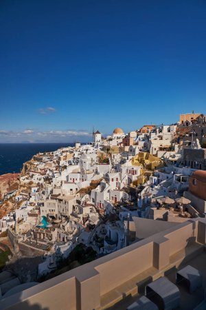 Photo for Beautiful panorama view from the old castle of Oia village with traditional white houses and windmills in Santorini island in Aegean sea at sunset, Greece - Royalty Free Image