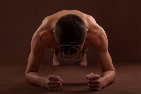 Photo for Handsome muscular shirtless adolescent boy doing plank exercise. - Royalty Free Image