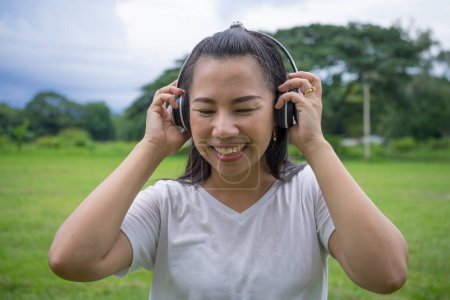 Photo for Good-looking asian young woman with no makeup having fun with favorite music outdoor. - Royalty Free Image