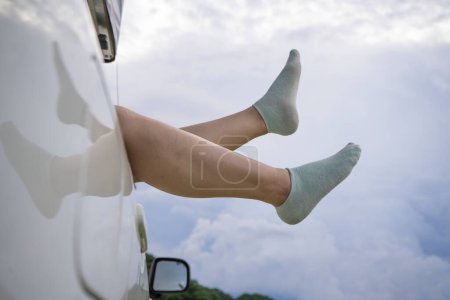 Photo for Feet of a asian girl in warm socks from the window of a car. Little holiday trip. - Royalty Free Image