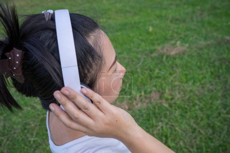Photo for Cute asian woman listen to music and holding white headphone, back shot. - Royalty Free Image