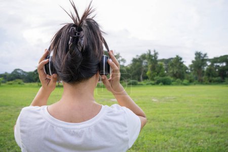 Photo for Cute asian woman listen to music and holding white headphone, back shot. - Royalty Free Image