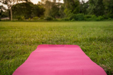 Photo for Pink mat for yoga or fitness on green grass lawn outdoors. - Royalty Free Image