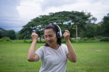 Photo for Good-looking asian young woman with no makeup having fun with favorite music outdoor. - Royalty Free Image