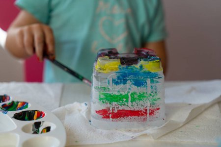 a child paints an ice castle with colored paints with a brush, close-up at home