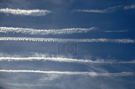 Photo for Ugly sky caused by multiple contrails from airplanes. Massive disfigurement of the sky, influencing of solar exposure, and air pollution of a normally blue sky, through air tourism and transportation. - Royalty Free Image