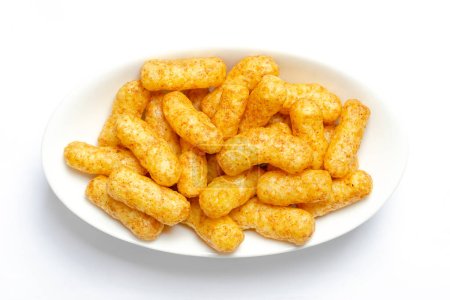 Peanut flips, in a white bowl. Also known as Bamba, peanut puffs or snips, is a puffed, peanut-flavored corn snack, with a peanut content up to a third. Close-up, from above, macro food photo.
