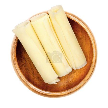 Photo for Sbrinz, Swiss hard cheese rolls, in a wooden bowl. Three rolled thin slices of extra hard full fat cheese, produced in central Switzerland, often used instead of Parmesan cheese. Close-up, from above. - Royalty Free Image