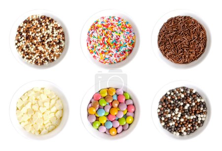 Sugar and chocolate sprinkles, in white bowls. Tiny chocolate balls, nonpareils, rod-shaped sugar and choco sprinkles, white choco hearts, and colorful button-shaped candies. Decoration and toppings.