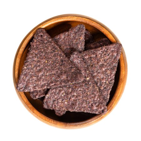 Photo for Blue tortilla chips, in a wooden bowl. Snack food, made from blue corn tortillas, cut into triangle shaped wedges, fried in oil and slightly salted. Close-up, from above, isolated, macro food photo. - Royalty Free Image