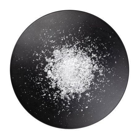 Photo for Sea salt, fleur de sel, in a flat black bowl. Also known as flor de sal, a salt that forms a thin, delicate crust on the sea water that evaporates. Used as a finishing salt to flavor and garnish food. - Royalty Free Image