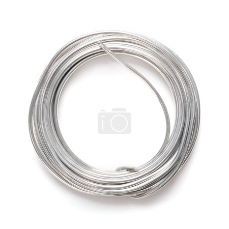 Photo for Rolled up soft solder wire. Fusible metal alloy with 60 percent tin, used to create a permanent bond between metal workpieces and for electrical connections. Close up, from above, on white background. - Royalty Free Image