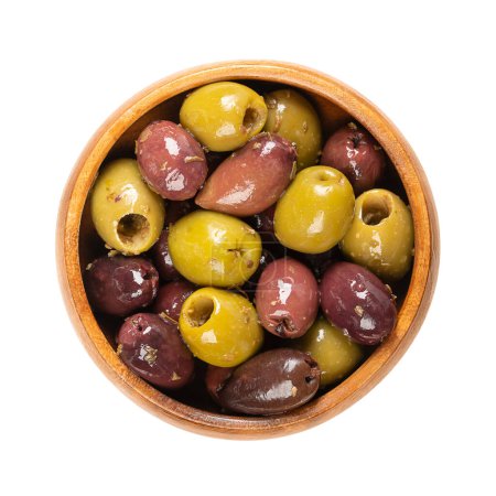 Entsteinte Kalamata und grüne Oliven in einer Holzschale. Mischung aus griechischen Bio-Oliven, grün und schwarz, mit Kräutern, in nativem Olivenöl konserviert. Beliebte Tafeloliven als Snack, Vorspeise oder Beilage.