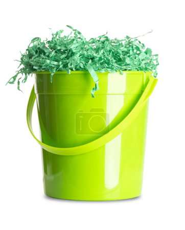 Photo for Paper Easter grass in a green plastic bucket. Vibrant colored and crinkled gift basket shred for filling and decoration, stuffed into the bucket, in the form of a nest. Close-up, front view. Photo. - Royalty Free Image