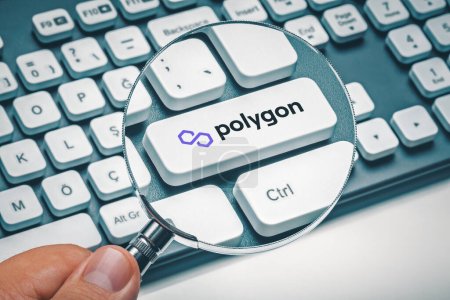 Male hand holding magnifying glass and focusing computer key with polygon token logo. Cryptocurrrency exchange or trading concept.