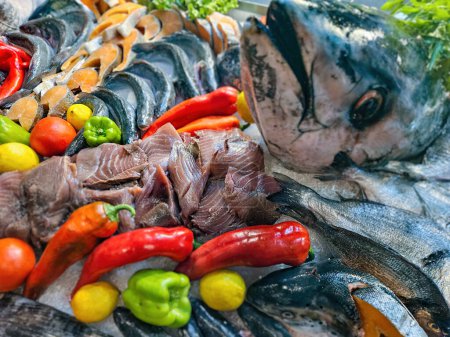 Téléchargez les photos : Décoration de fruits de mer avec saumon cru, thon, daurade et autres poissons arrangés avec des légumes sur glace dans l'affichage du restaurant. - en image libre de droit