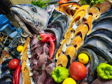 Téléchargez les photos : Décoration de fruits de mer avec saumon cru, thon, daurade et autres poissons arrangés avec des légumes sur glace dans l'affichage du restaurant. - en image libre de droit