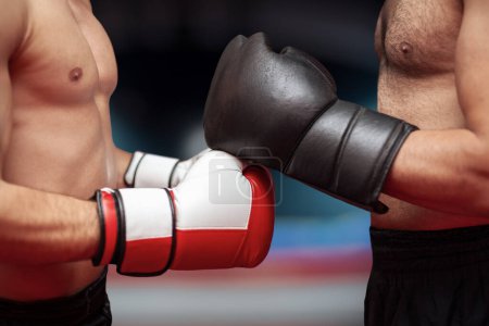 Photo for Two boxers before the start of a match in in front of blurry ring . Martial arts, fitness or MMA concept.  Fighters before the competition begins. Boxers greeting each other. - Royalty Free Image