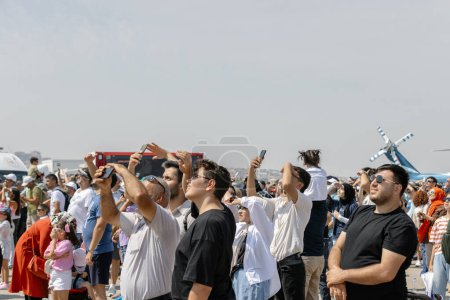 Téléchargez les photos : Ankara-Turquie : 02 septembre 2023 : foule excitée regardant le spectacle aérien de F-16 Fighting Falcon avec des yeux curieux et prenant des photos à Teknofest Ankara - en image libre de droit