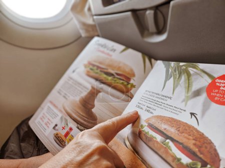 Téléchargez les photos : Ankara-Turquie : 15 octobre 2023 : Passagère regardant le menu à bord et commandant un sandwich pendant un vol dans l'avion. - en image libre de droit