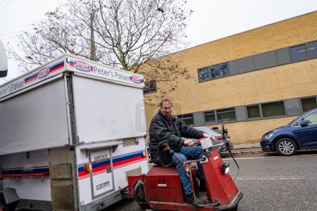 Foto de Copenhague, Dinamarca Un hombre tira de un pequeño vagón de perritos calientes en la calle con un scooter pequeño. - Imagen libre de derechos