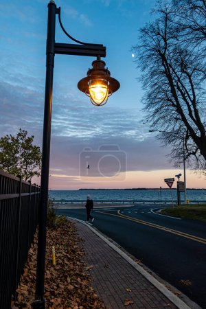 Foto de Solomons, Maryland, Estados Unidos Un hombre camina bajo un poste de luz en una pequeña calle en el paseo marítimo del río Patuxent. - Imagen libre de derechos