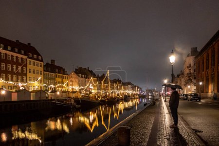 Téléchargez les photos : Copenhague, Danemark Un touriste célibataire se tient dans le quartier Nyhavn la nuit. - en image libre de droit
