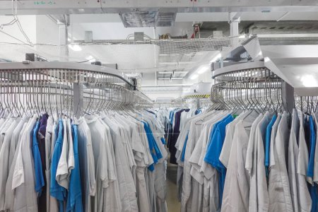 Kopenhagen, Dänemark Medizinische Outfits auf automatischen Regalen in einer chemischen Reinigungsanlage in einem Krankenhaus.
