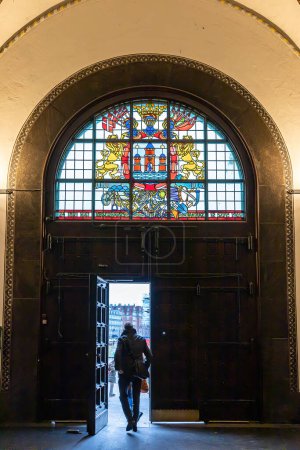 Téléchargez les photos : Copenhagen, Denmark  A person walks under a stained glass window in the main hallway of the  Copenhagen City Hall representing the three original towers of the city. - en image libre de droit
