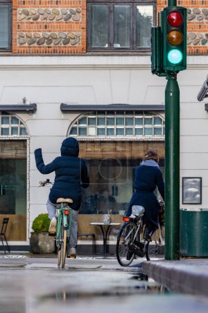 Foto de Copenhagen, Denmark Feb 1, 2023 A bicyclist at a street crossing and intersection uses hand signals to mark intent. - Imagen libre de derechos