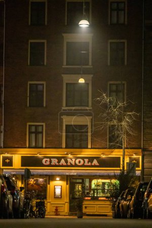 Téléchargez les photos : Copenhagen, Denmark  A pedestrian walks by the  landmark Granola restaurant at night on Varnedamsvej. - en image libre de droit