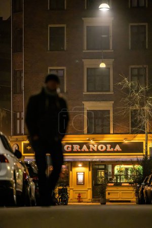 Téléchargez les photos : Copenhagen, Denmark  A pedestrian walks by the  landmark Granola restaurant at night on Varnedamsvej. - en image libre de droit