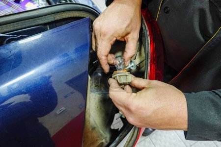 Foto de Solomons, Maryland EE.UU. Un mecánico en un garaje de automóviles arregla una luz trasera rota. - Imagen libre de derechos