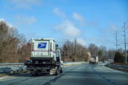 Foto de Solomons, Maryland, EE. UU. Un remolque lleva una furgoneta postal estadounidense en su cama plana. - Imagen libre de derechos