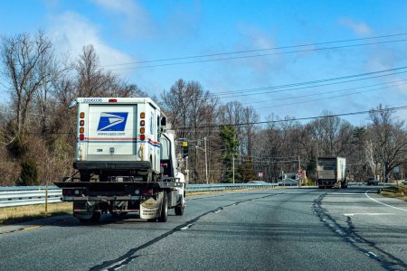 Foto de Solomons, Maryland, EE. UU. Un remolque lleva una furgoneta postal estadounidense en su cama plana. - Imagen libre de derechos