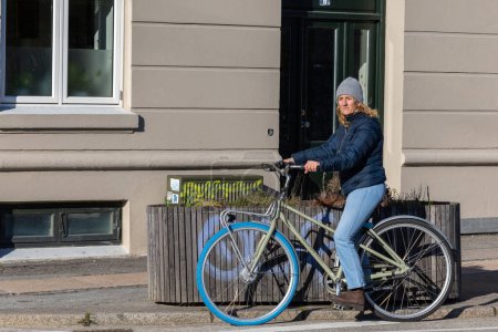 Photo for Copenhagen, Denmark  A Danish woman rides a bicycle. - Royalty Free Image