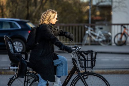 Téléchargez les photos : Stockholm, Suède Une femme cycliste vérifie sa montre à un feu rouge. - en image libre de droit