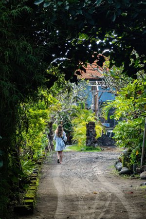 Téléchargez les photos : Canggu, Bali, Indonésie, Une jeune étrangère descend une ruelle luxuriante. - en image libre de droit