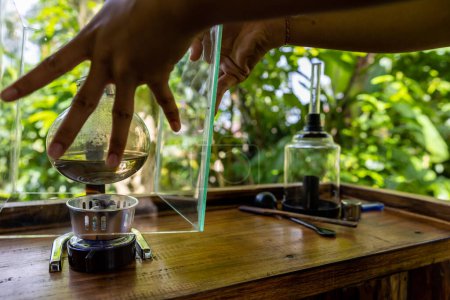 Téléchargez les photos : Bali, Indonésie Une femme prépare du café Luwak dans une plantation de café pour la dégustation par percolation. - en image libre de droit