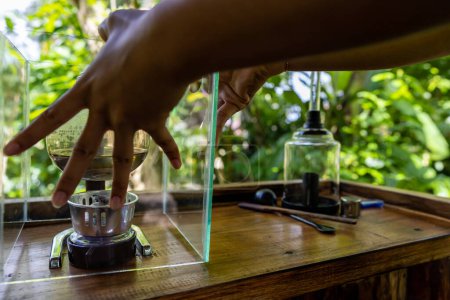 Téléchargez les photos : Bali, Indonésie Une femme prépare du café Luwak dans une plantation de café pour la dégustation par percolation. - en image libre de droit