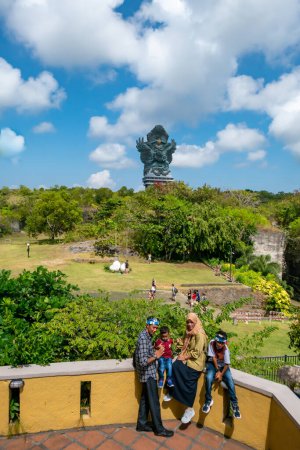 Téléchargez les photos : Bali, Indonésie, Une famille asiatique pose dans le parc culturel GWK à l'extérieur de Denpasar avec des statues de dieux hindous. - en image libre de droit