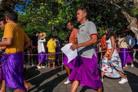 Foto de Uluwatu, Bali, Indonesia Turistas con sarongs obligatorios esperan en fila en el templo de Uluwatu - Imagen libre de derechos