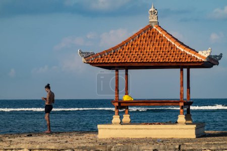 Téléchargez les photos : Sanur, Bali, Indonésie Un touriste se tient à côté d'une petite pagode sur la plage de Sanur. - en image libre de droit