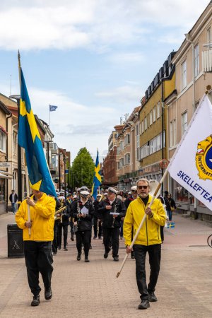 Téléchargez les photos : Skelleftea, Suède Des gens portant des drapeaux suédois lors d'une procession de la fête nationale dans les rues. - en image libre de droit