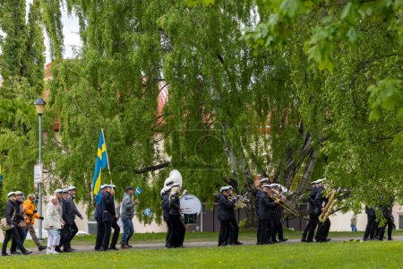 Téléchargez les photos : Skelleftea, Suède Des gens portant des drapeaux suédois lors d'une procession de la fête nationale dans les rues. - en image libre de droit