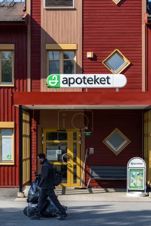 Téléchargez les photos : Skelleftea, Suède Un homme portant de grands sacs en plastique sur un scooter électrique passe devant l'Apoteket ou la pharmacie suédoise. - en image libre de droit