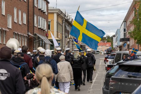Téléchargez les photos : Skelleftea, Suède 6 juin 2023 Personnes portant des drapeaux suédois lors d'une procession de la fête nationale dans les rues. - en image libre de droit